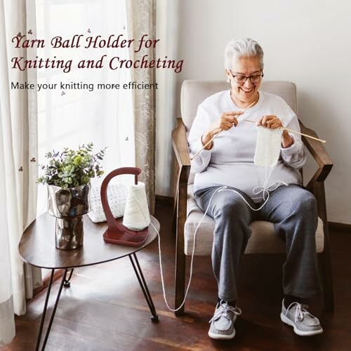 Person knitting with a yarn ball holder beside them on a table.